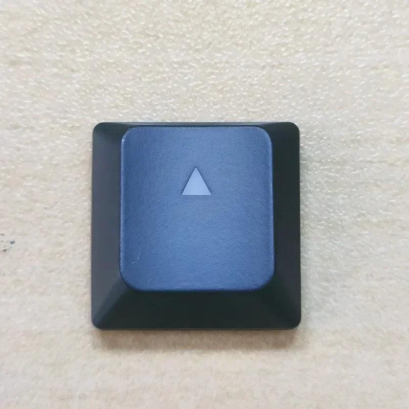 A close-up view of a blue replacement keycap with a triangular shape for a Dell Alienware keyboard.