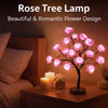 A Rose Tree lamp with pink glowing flowers illuminates a bedside table.