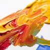 Close-up of vibrant yellow, orange, and red gouache paint strokes on white paper.