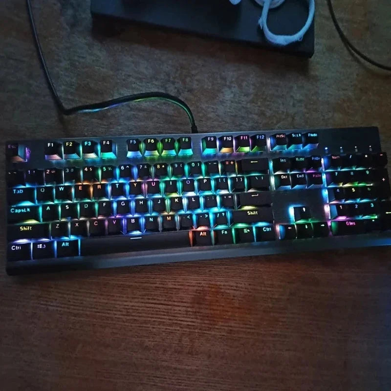 A close-up shot of a black mechanical keyboard with colorful RGB backlighting resting on a wooden surface.