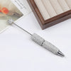 A silver rhinestone beaded pen accessory with a decorative head is displayed on a white surface next to a wooden box and a bo