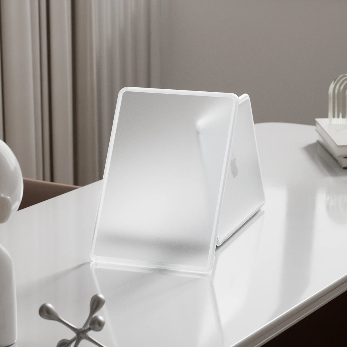 A clear, hard shell laptop case for a MacBook is displayed on a white table.