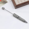 A silver pen accessory featuring a rhinestone ball and a beaded tip, displayed on a white surface.