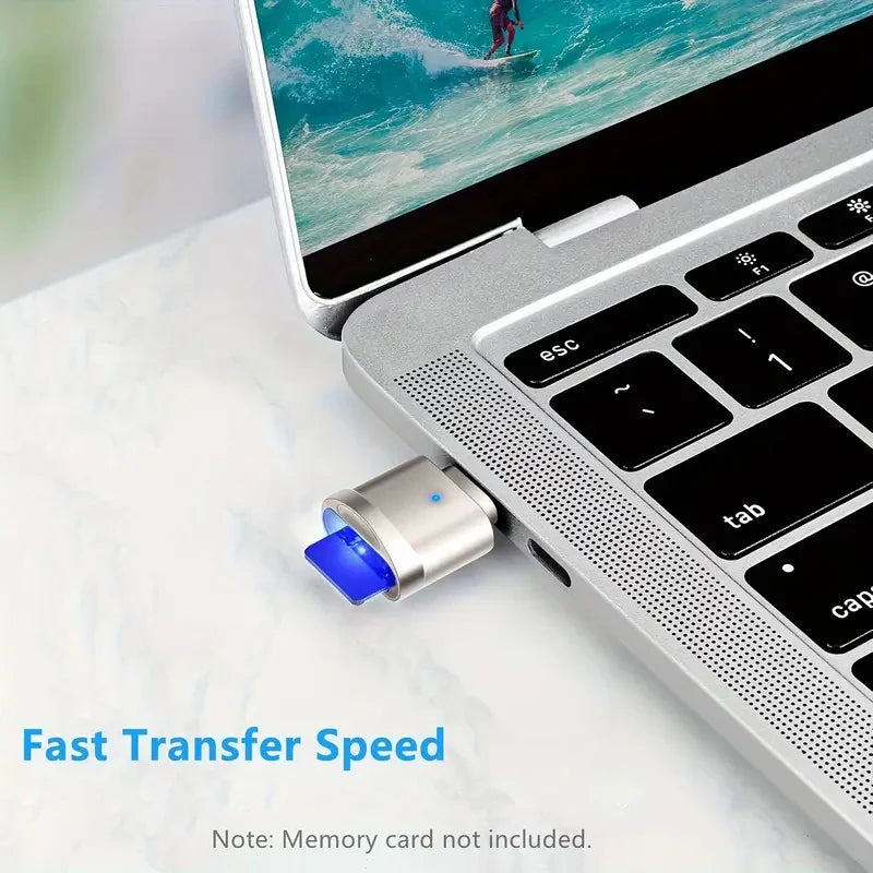 حاسوب محمول فضي مع قارئ بطاقة USB-C خارجي بجانب عرض لمياه المحيط.