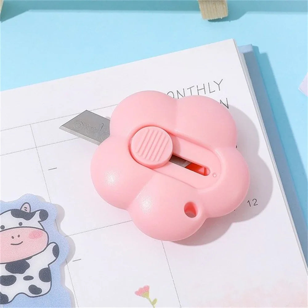 A pink floral design letter opener and paper cutter resting on a white monthly planner page.