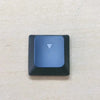 A dark blue replacement keycap with a white triangle marker for a Dell Alienware keyboard.