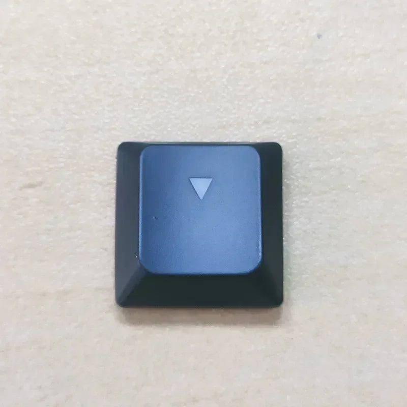 A dark blue replacement keycap with a white triangle marker for a Dell Alienware keyboard.