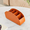 An orange plastic remote control holder and desk organizer tray resting on a white marble surface.