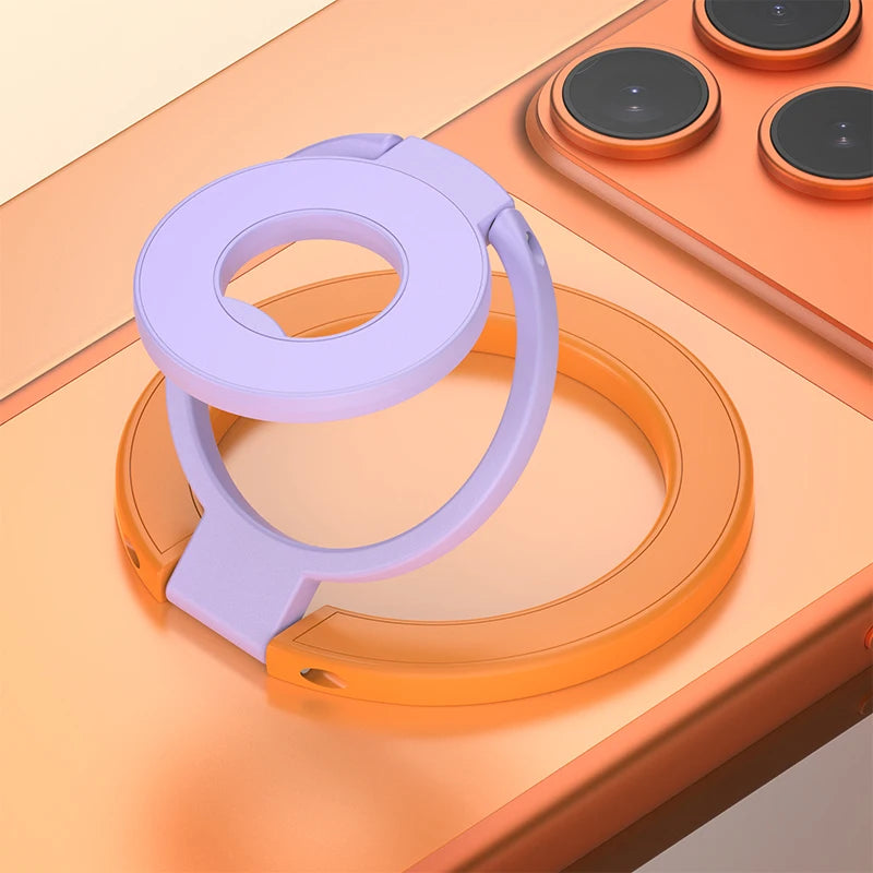 A purple phone ring holder stand is shown resting on an orange surface next to a charging pad.