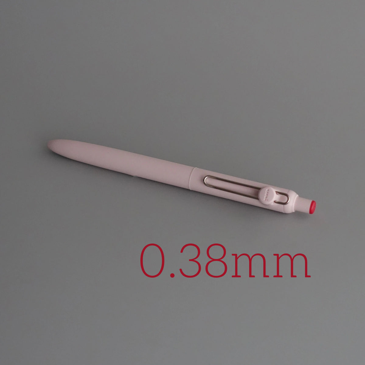 A close-up view of a light pink precision gel pen with quick-drying ink, showing its size as 0.38mm.