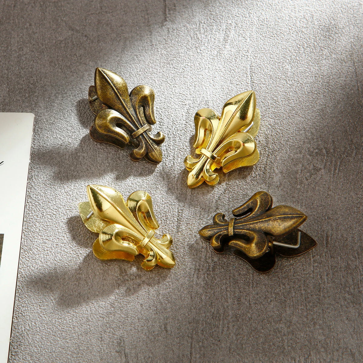 A set of two decorative iris-shaped metal binder clips in gold and bronze tones.