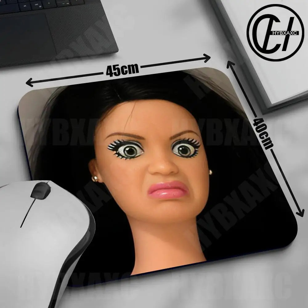 A close-up of a cute doll face mouse pad with a non-slip rubber base shown next to a laptop and a computer mouse.