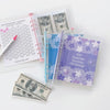 A set of 100 envelope savings challenge trackers and a stack of US dollar bills are displayed on a white background.