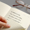 A close-up of an open A5 Kraft cover notebook showing handwritten Chinese text and a pair of eyeglasses.