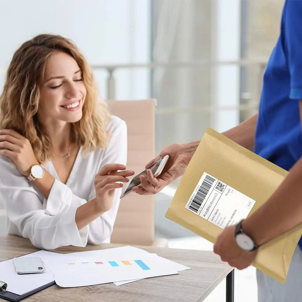 A woman is handing a kraft paper bubble mailer to another person in an office setting.