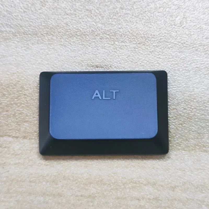 A dark blue replacement keycap labeled ALT resting on a light beige fabric surface.