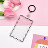 A clear acrylic card holder with a black keychain ring resting on a pink background.