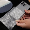 Hands are unwrapping a smartphone with clear bubble wrap protective padding.