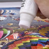 Eine Hand trägt starken Klebstoff auf ein Diamantmal-Puzzle-Stück auf.