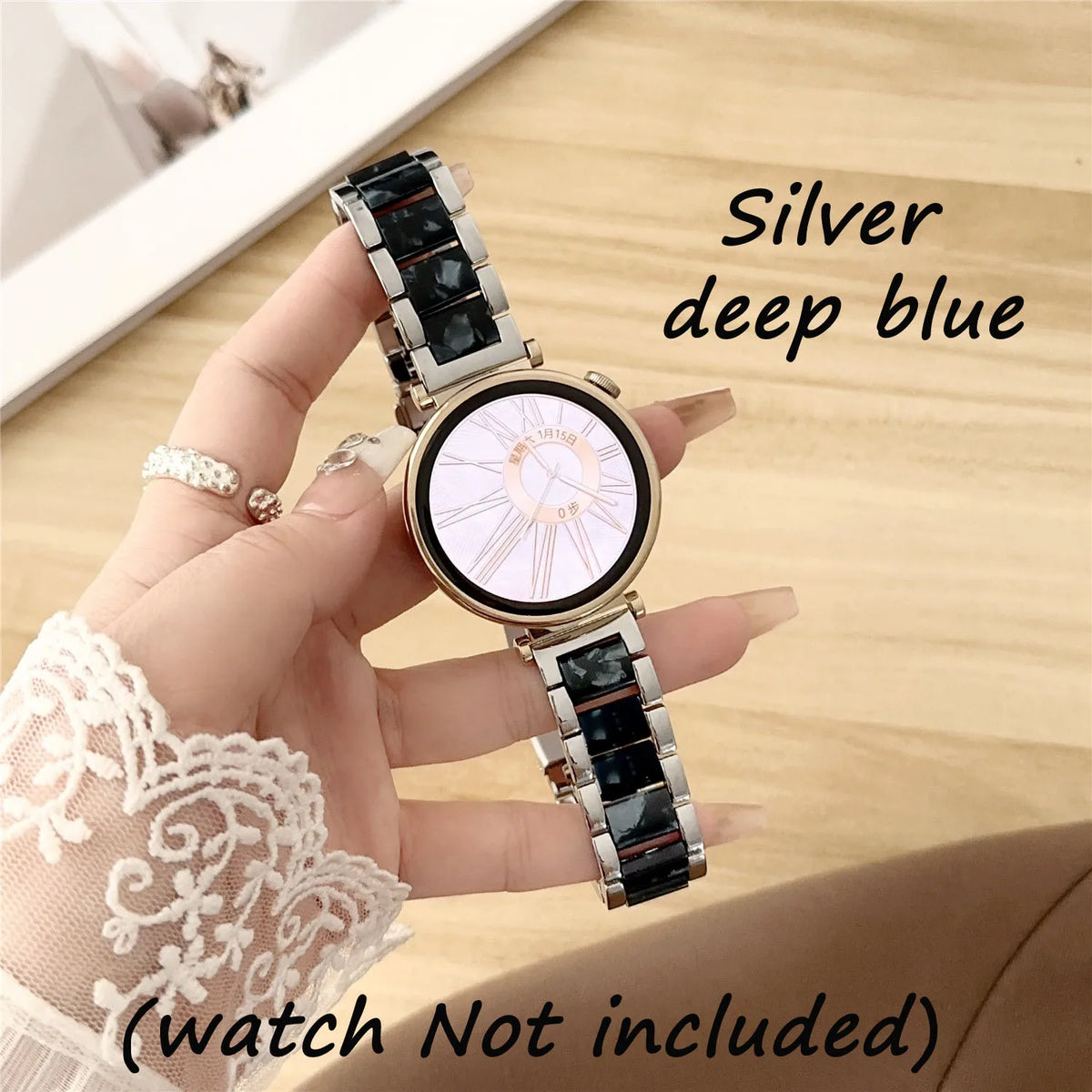 Eine Hand hält eine silberne Uhr mit tiefblauen Harzbändern und weißem Zifferblatt vor einem Holz-Hintergrund.