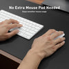 Hands are using a white wireless mouse on a black desk mat next to a white keyboard.