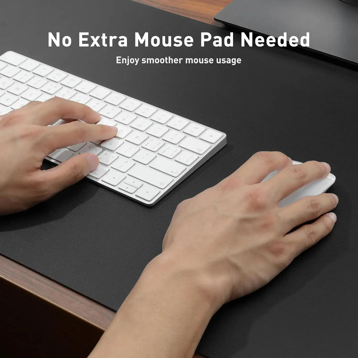 Hands are using a white wireless mouse on a black desk mat next to a white keyboard.