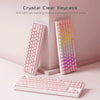 Pink and white crystal clear mechanical keyboard keycaps displayed on a desk with RGB lights glowing.