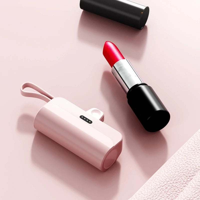 A pink portable DIY power bank shell next to a black cosmetic tube and a black cylindrical object.