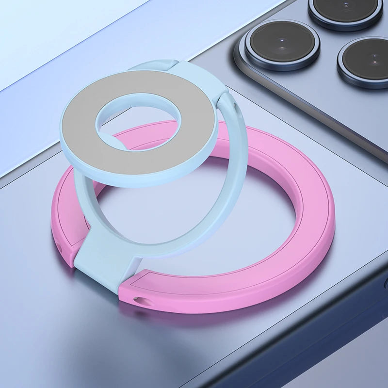 A pink and white magnetic ring grip with a foldable kickstand shown on a gray surface.