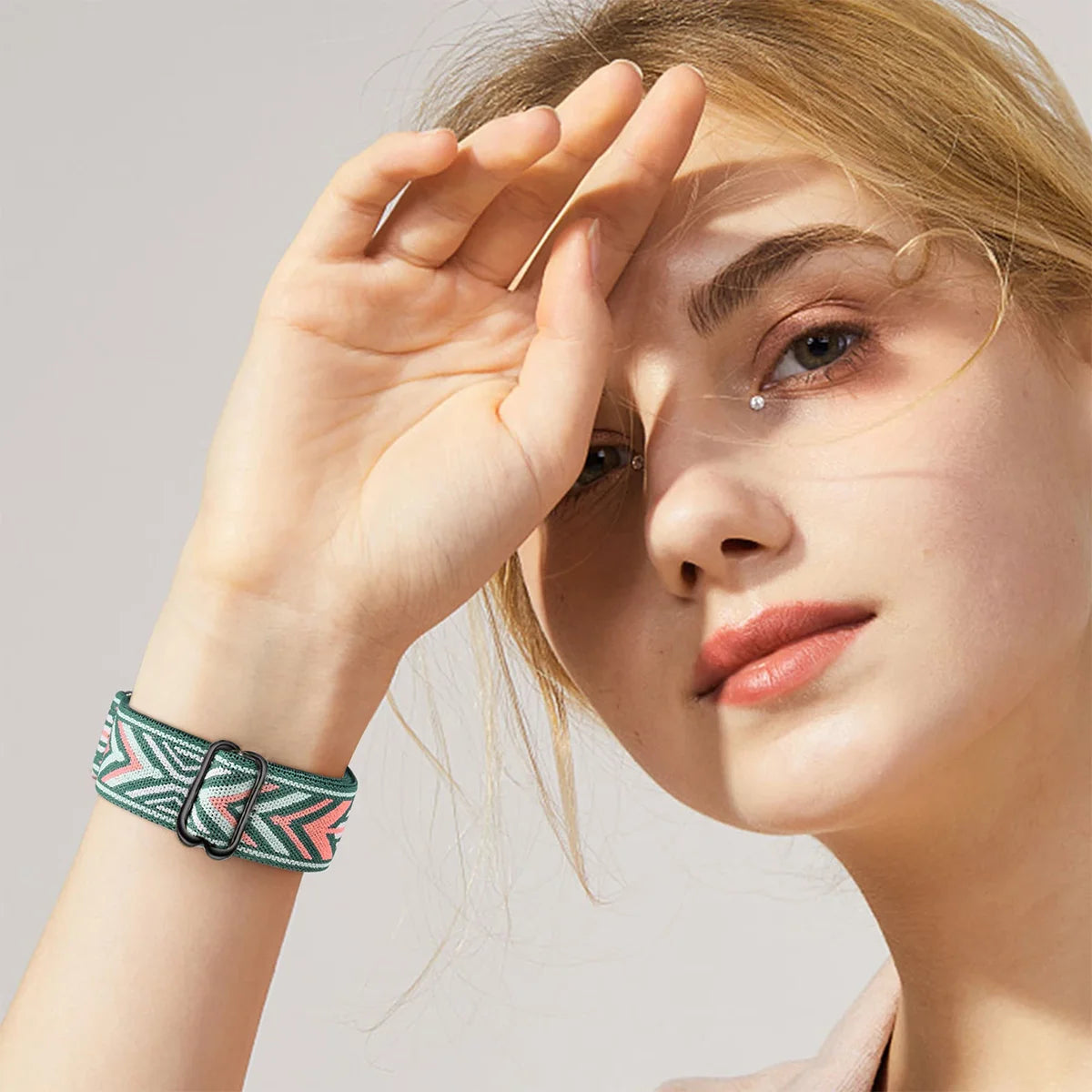 A woman wearing a green and pink patterned elastic sports band on her wrist.