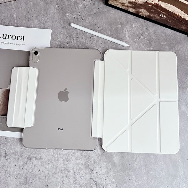 Silberes iPad mit weißer Schutzhülle und Stift auf grauer Betonoberfläche.