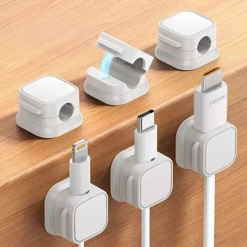 A set of white magnetic cable organizer clips and a charging cable are shown on a wooden surface.