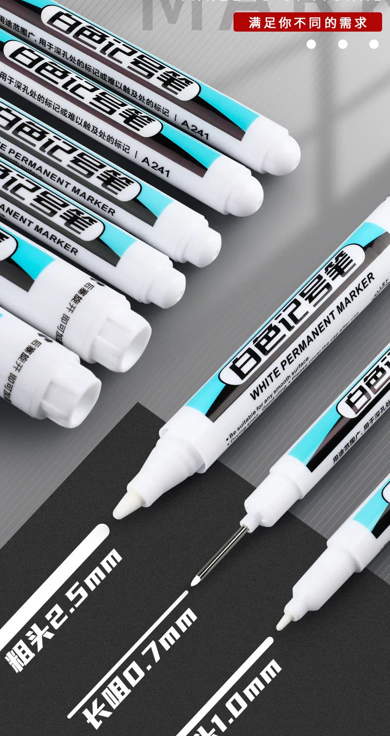 A close-up view of several white permanent paint marker pens with various tips and sizes displayed on a dark surface.