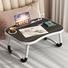 A multi-functional laptop desk organizer tray with a wooden surface holding a laptop, a cup, and art supplies.