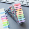 A clear plastic pack of colorful fluorescent tabs and markers in various pastel shades lying on a gray desk.