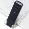 A black USB rechargeable LED book reading light is shown resting on a white page.