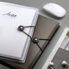 Une pile de carnets à feuilles détachées et une boucle élastique avec une souris d'ordinateur blanche sur un fond gris.
