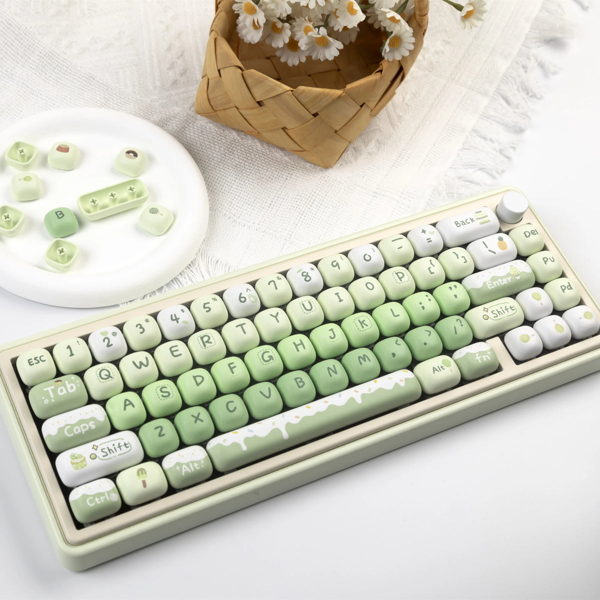 A close-up of a light green mechanical keyboard featuring colorful PBT keycaps and a white keycap set.
