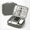 A gray travel cable organizer bag with an open compartment showing various electronic cables and accessories.