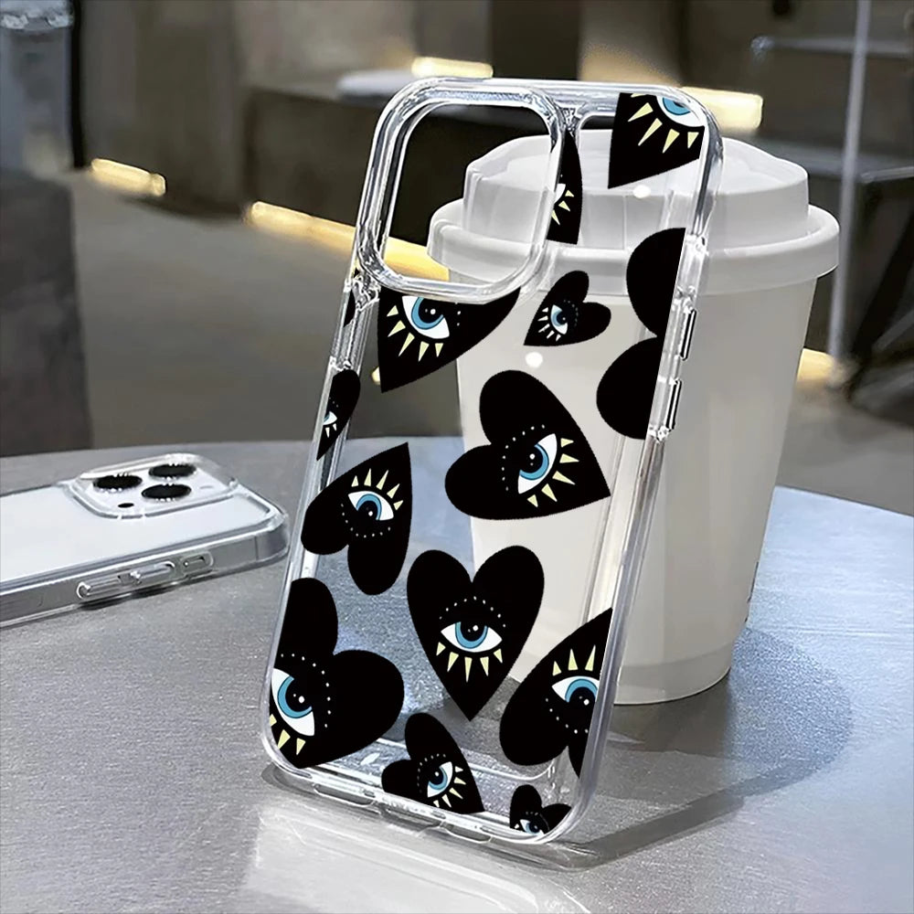 A clear phone case with a black and white floral pattern is placed next to a white cup.