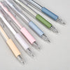A collection of precision utility knives with various colored handles and silver tips arranged diagonally on a light gray sur
