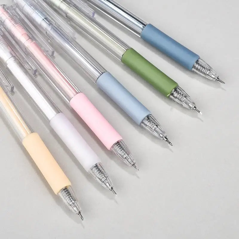 A collection of precision utility knives with various colored handles and silver tips arranged diagonally on a light gray sur