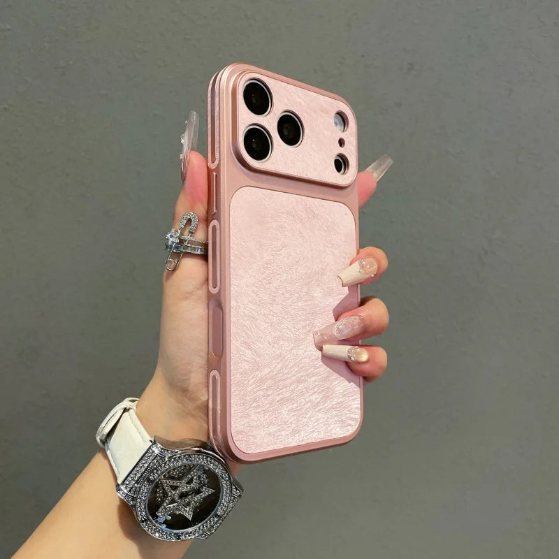 A hand holds a pink frosted velvet texture phone case with a silver watch on a gray background.