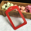 Red PU leather ID card holder with a cutout shape resting on a wooden tray filled with pink and white roses.