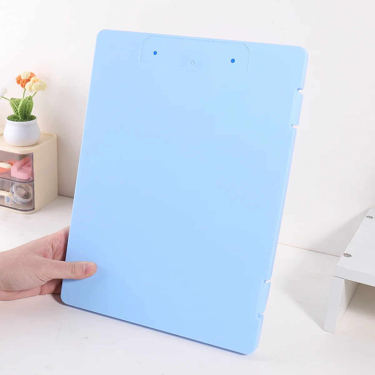 A light blue A4 document and photo storage file box is shown being held by a hand.