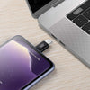 A close-up of a silver laptop next to a purple smartphone with a USB-C adapter plugged in.