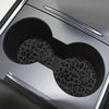 Close-up view of a silver car cup holder with two leopard print non-slip leather coasters visible inside.