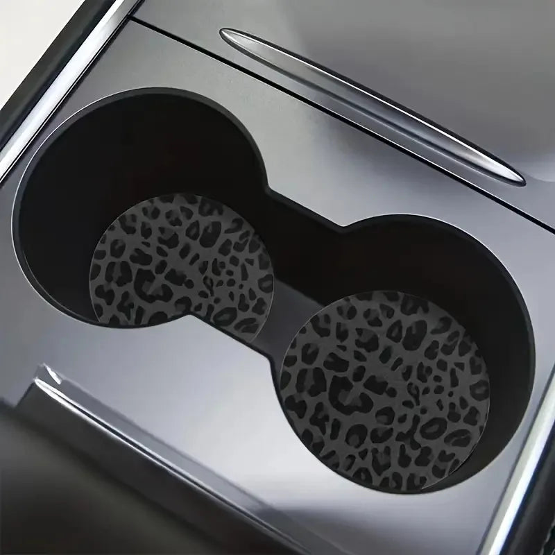 Close-up view of a silver car cup holder with two leopard print non-slip leather coasters visible inside.