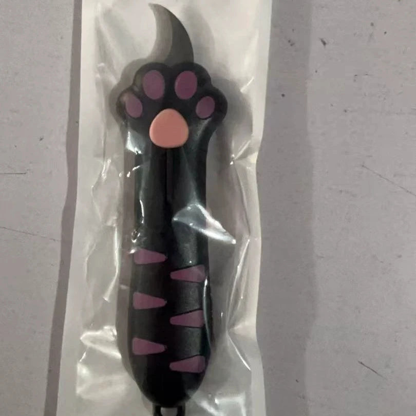 A black cat paw-shaped box cutter with a titanium steel blade is shown inside clear plastic packaging.