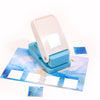 A white embossing punch machine with a blue base and several small blue and white patterned stamps on a light blue craft shee